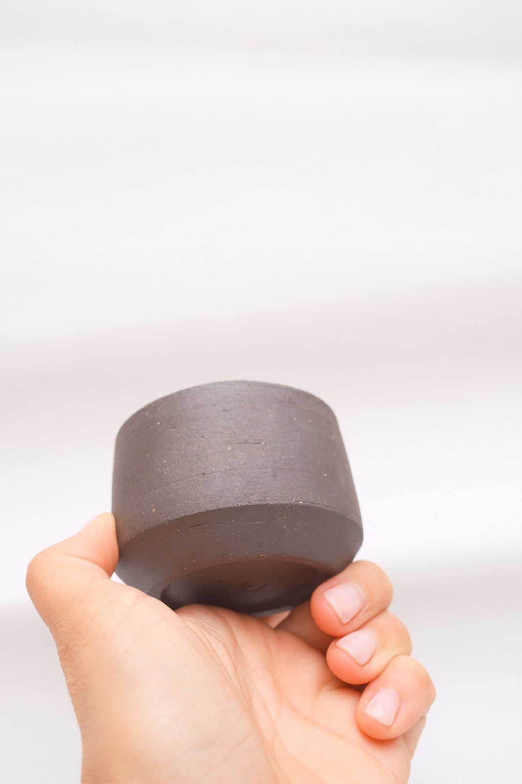 The cup held upside down, showing the raw dark clay foot
