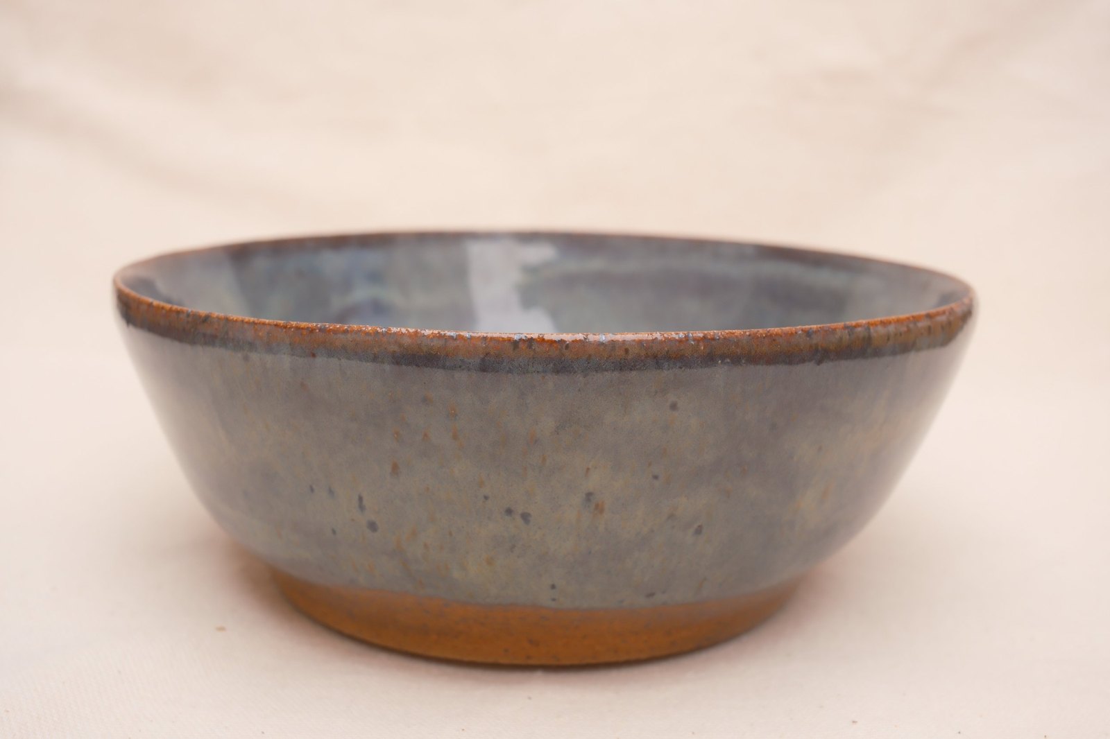 Close side view of the rust-speckled rim and glaze drips