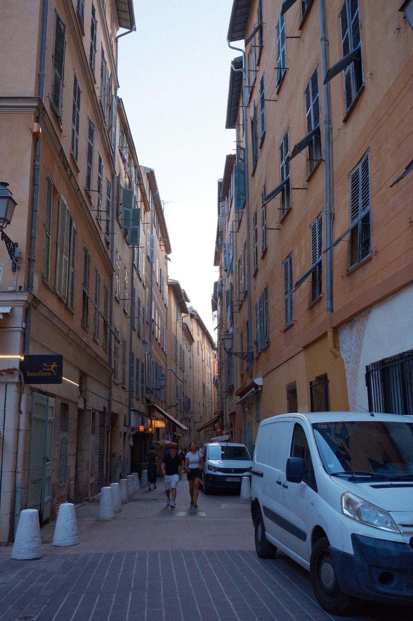A tall, narrow Old Town street of ochre facades and green shutters