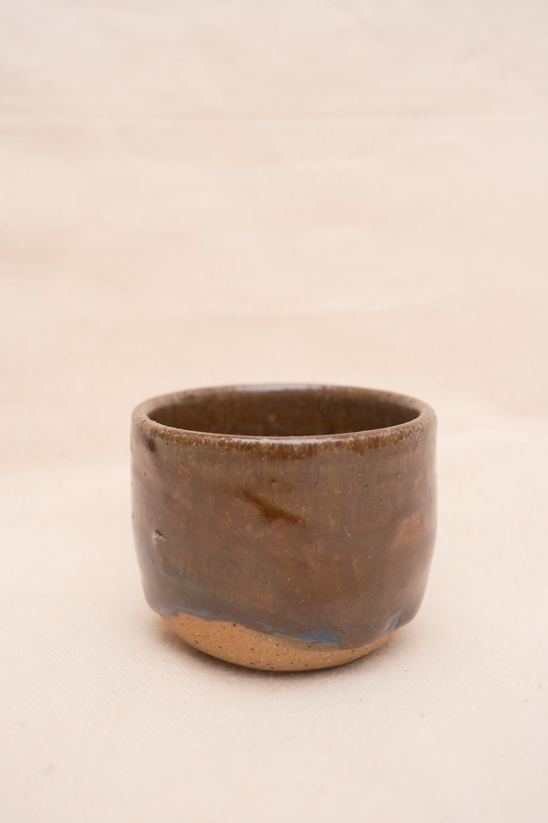 Amber cup turned to show glaze drips and a thumb dimple