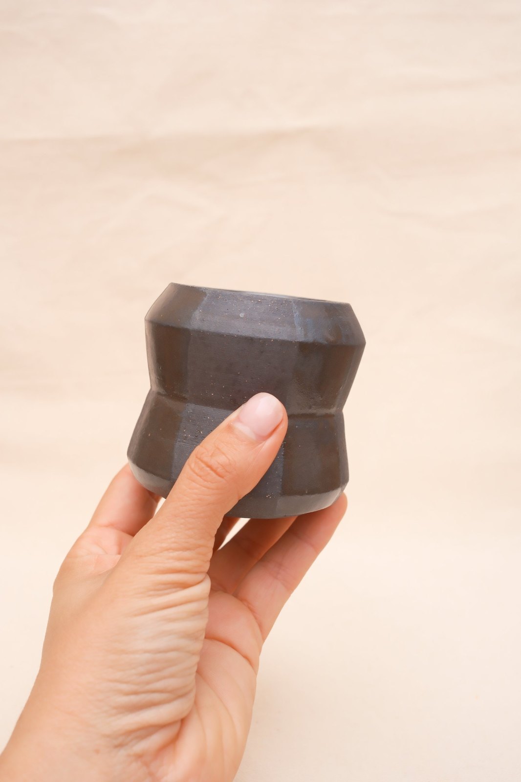 The cup held in one hand, showing its size