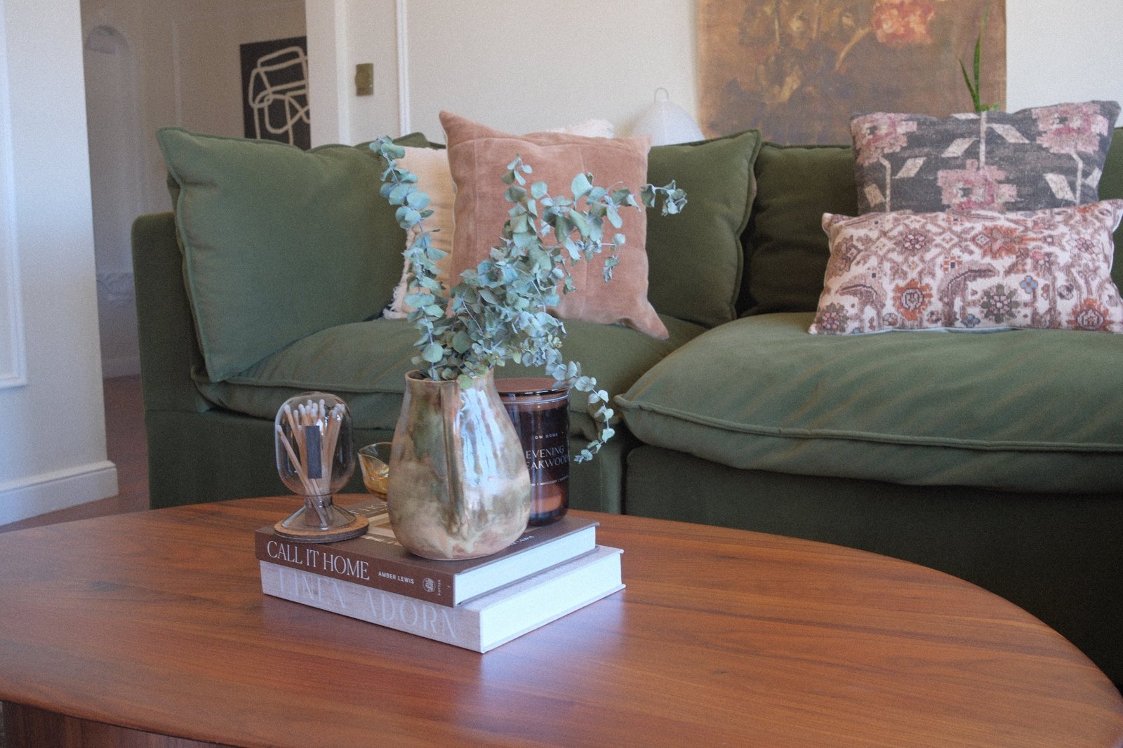 Walnut coffee table styled with a glazed pitcher of eucalyptus, match cloche and stacked design books