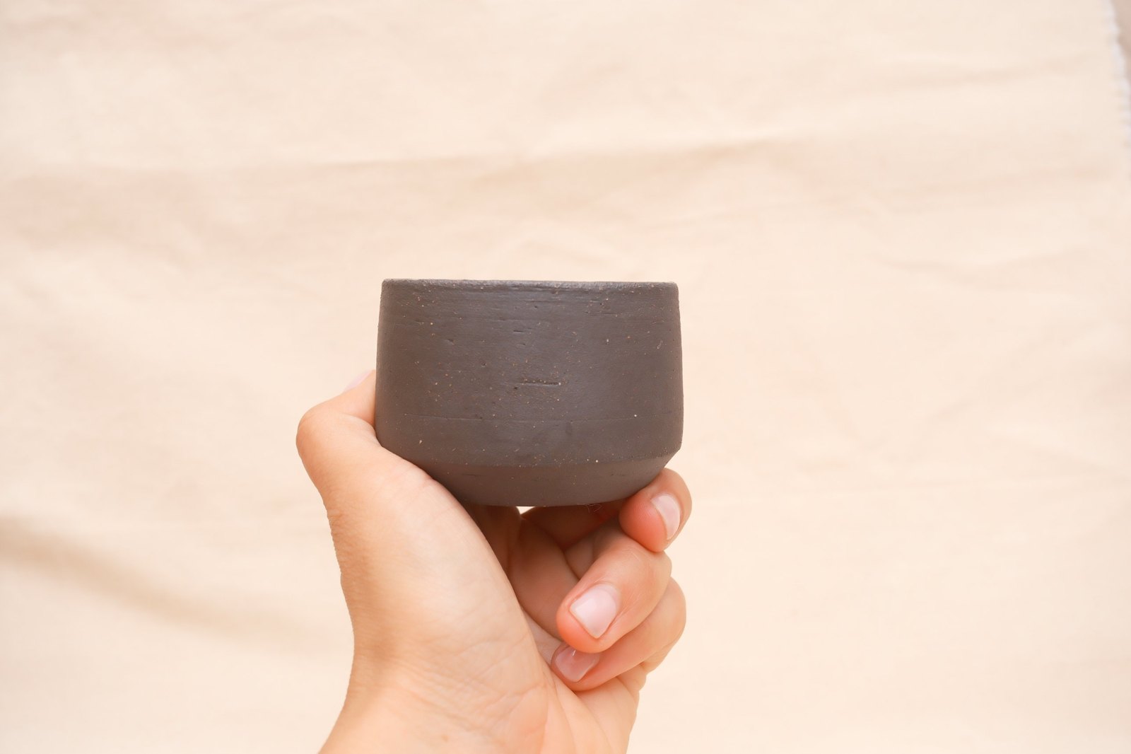The cup held at eye level, raw clay outside