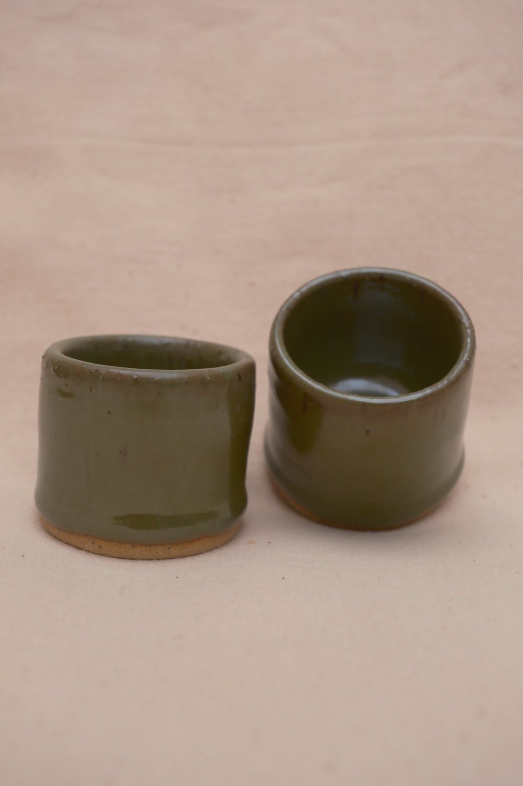 Close view of the pair in deeper olive tones, one glass angled to show the glossy interior