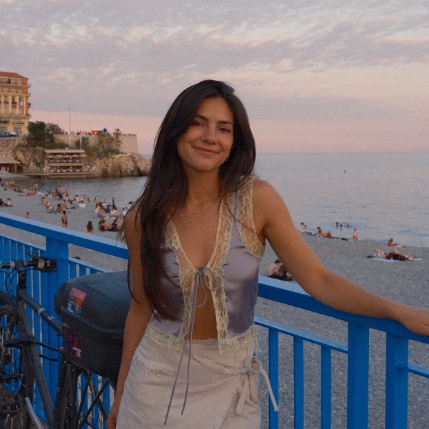 Sanoma smiling at the blue railing above the beach in Nice at sunset