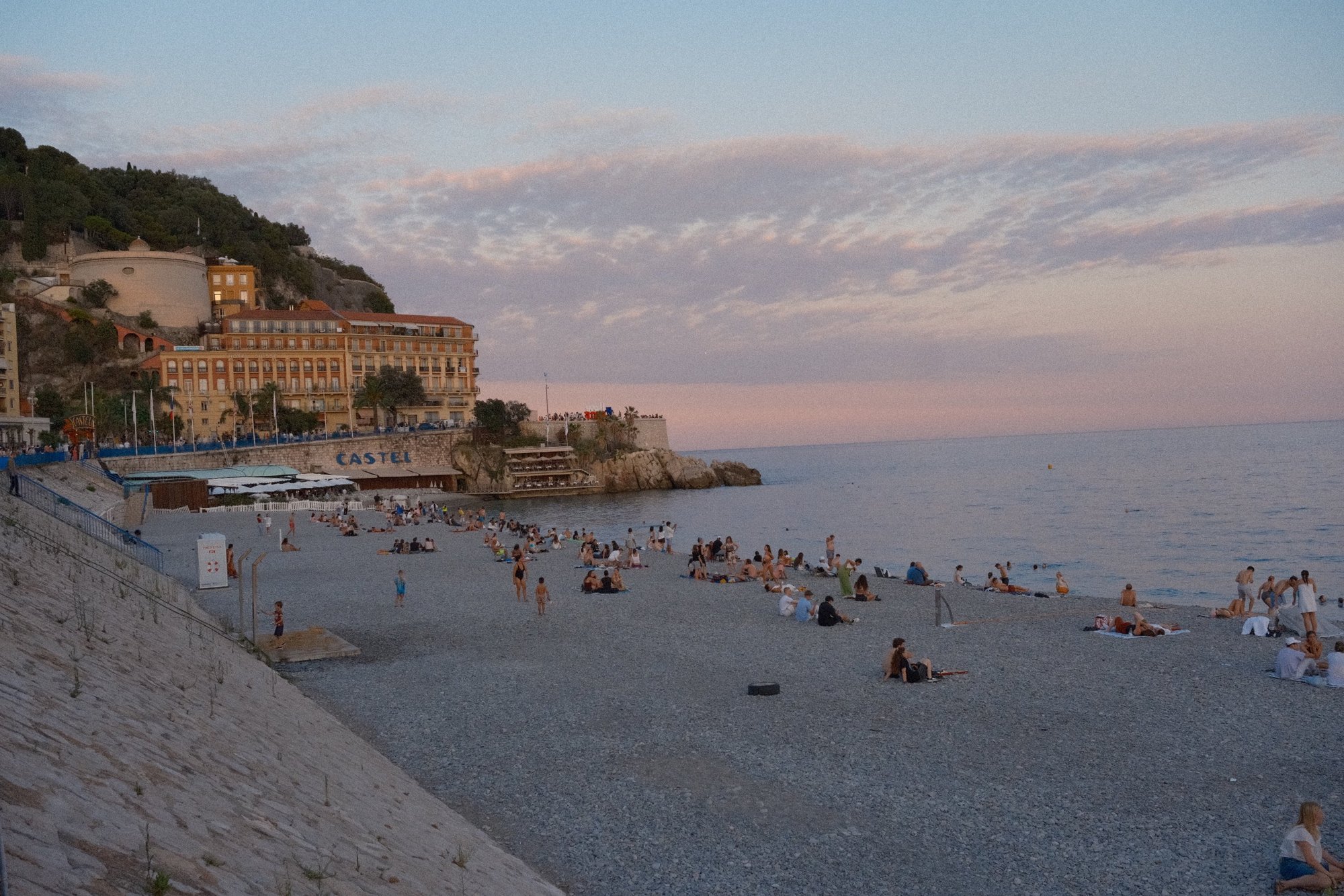 The pebble beach below Castle Hill under a pink-and-lavender sunset sky