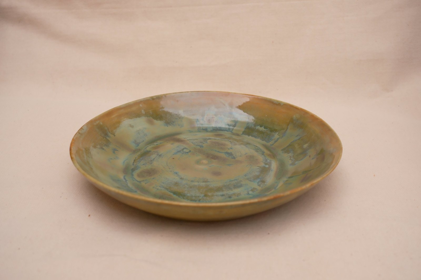 The plowl from a low angle, glaze breaking from green-gold to turquoise