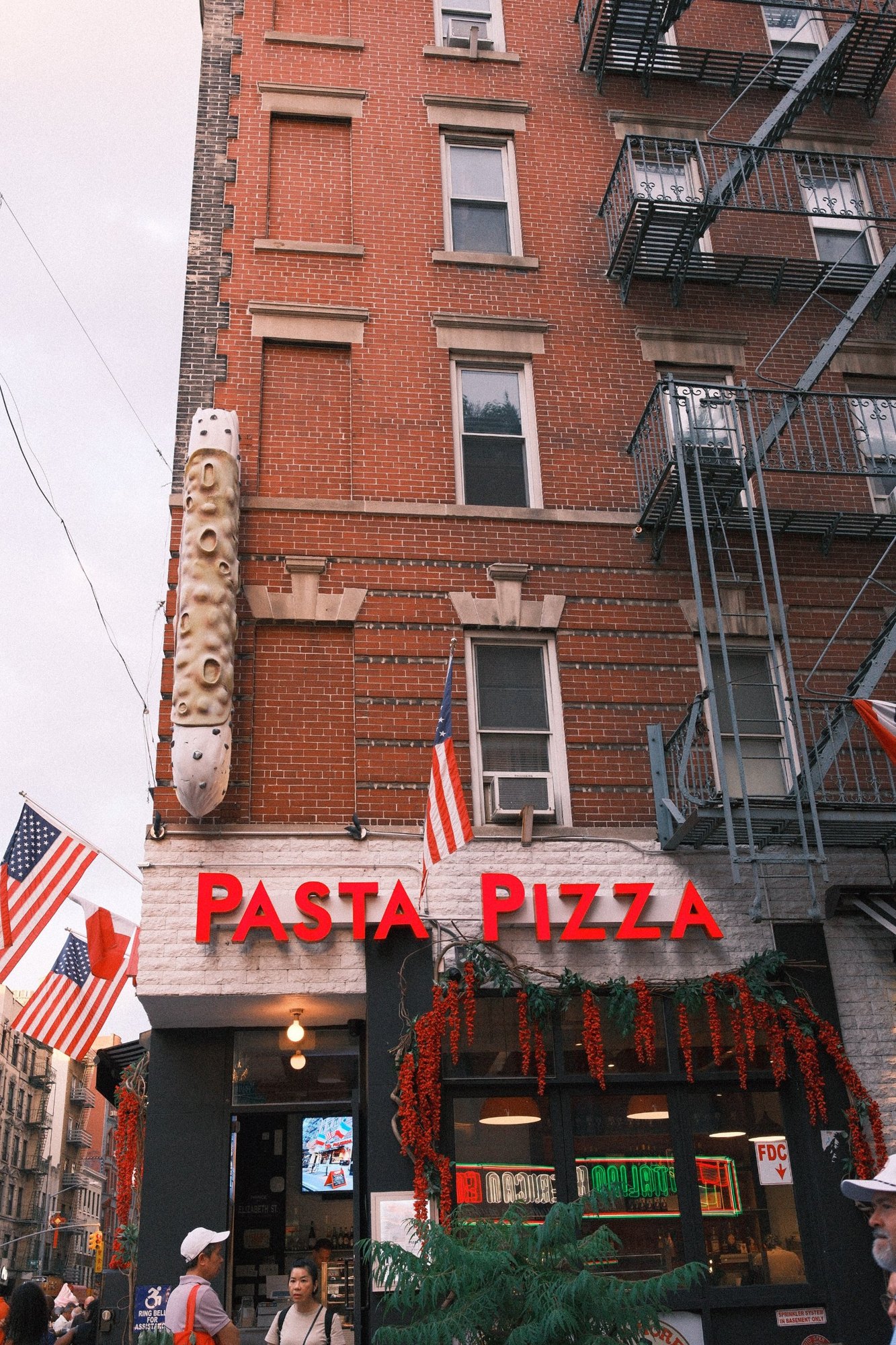 Pasta Pizza sign under a giant cannoli on a red-brick corner