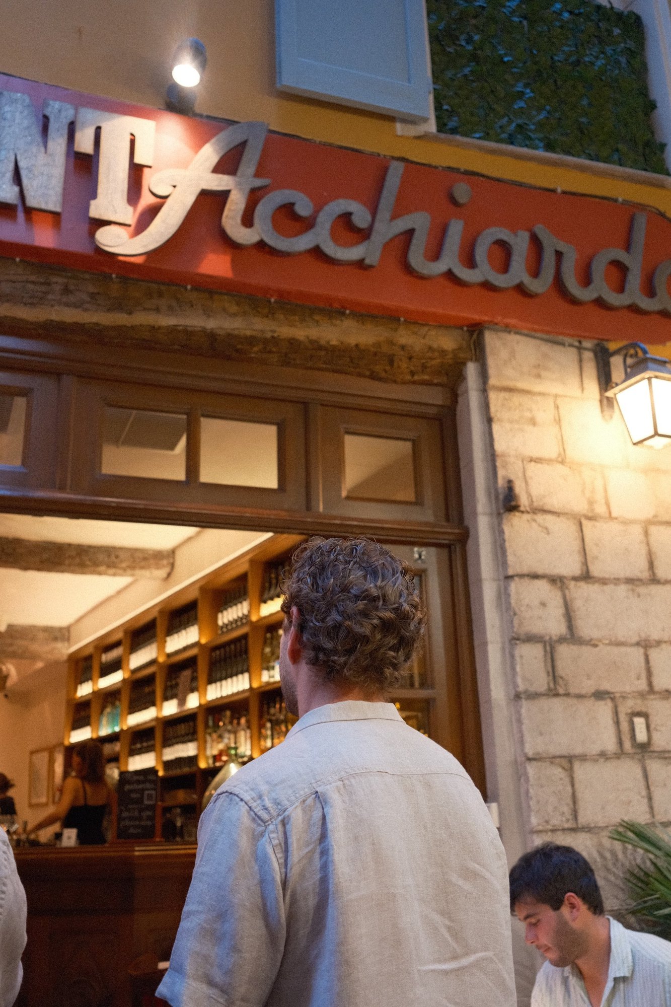 Waiting at the door under Acchiardo's red script sign