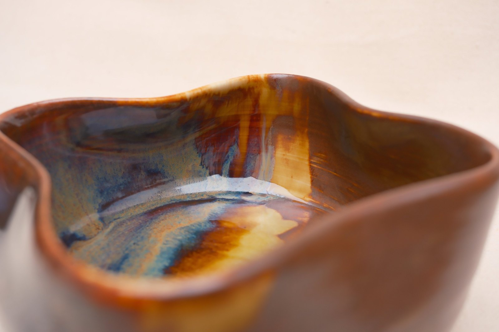 Close view inside the bowl: amber, rust and blue glaze running together