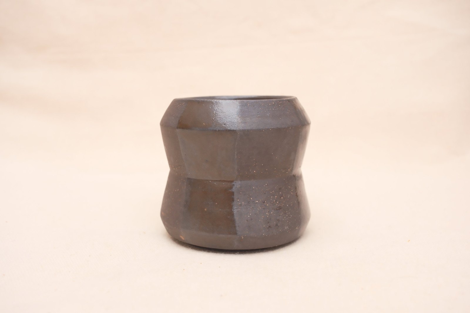 The cup straight on, speckles in the raw clay