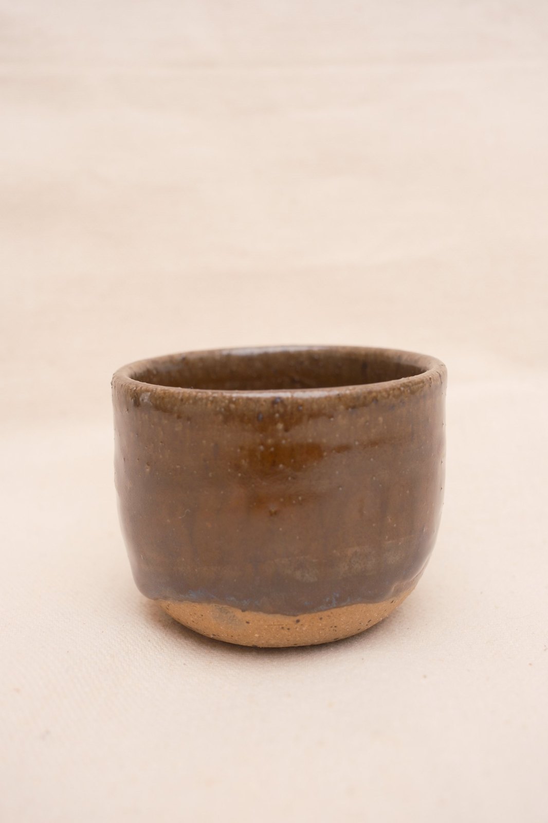 Amber cup from the reverse side, glaze pooling above the speckled foot