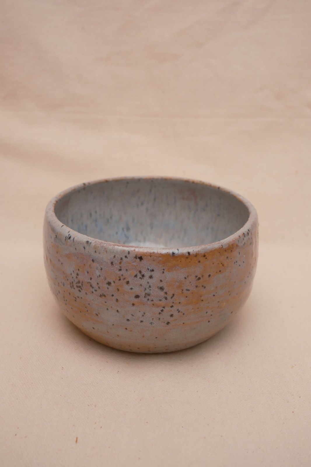 Small speckled blue trinket bowl with hints of pink, on linen