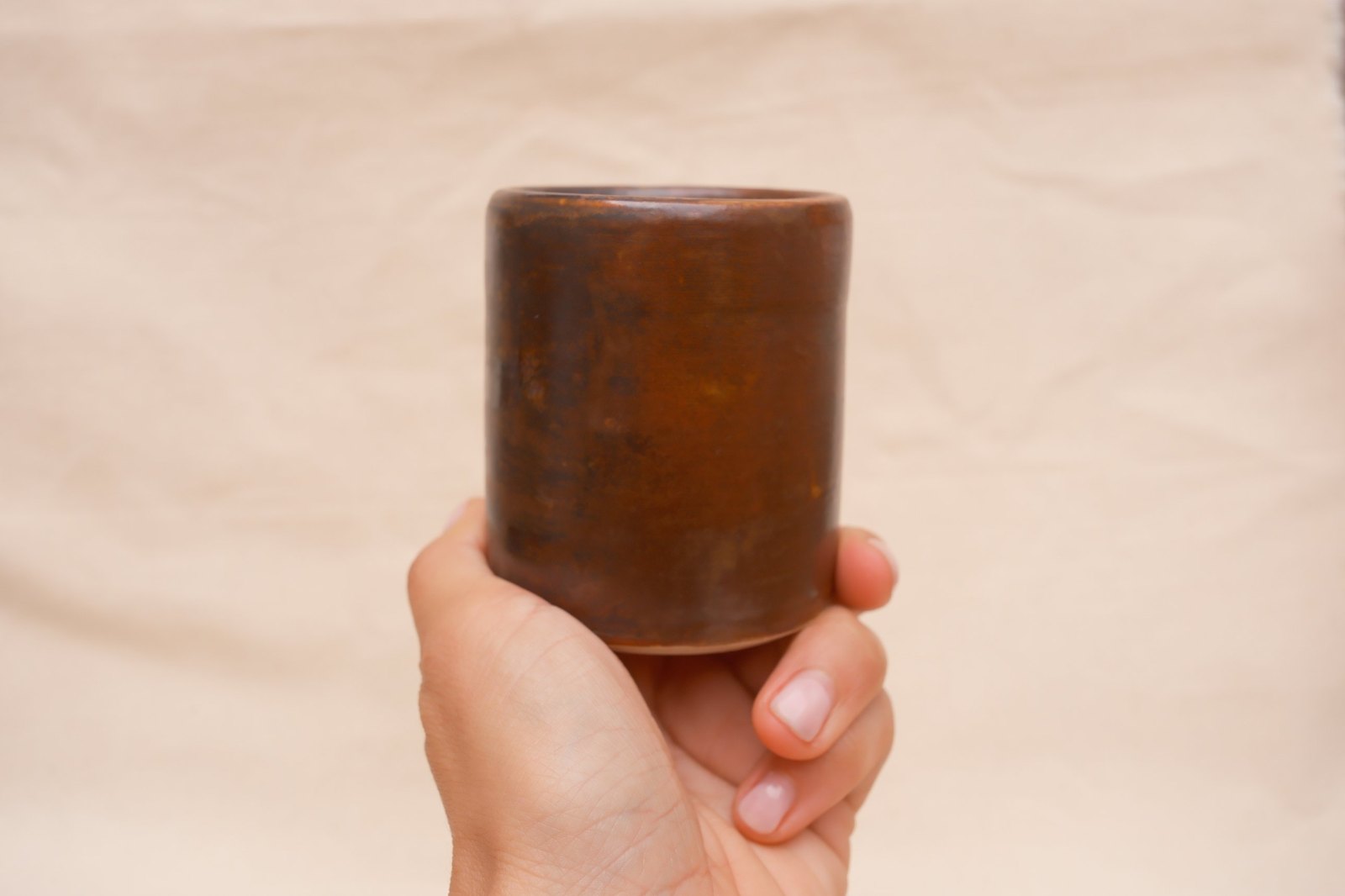 The cup in hand against linen, straight on