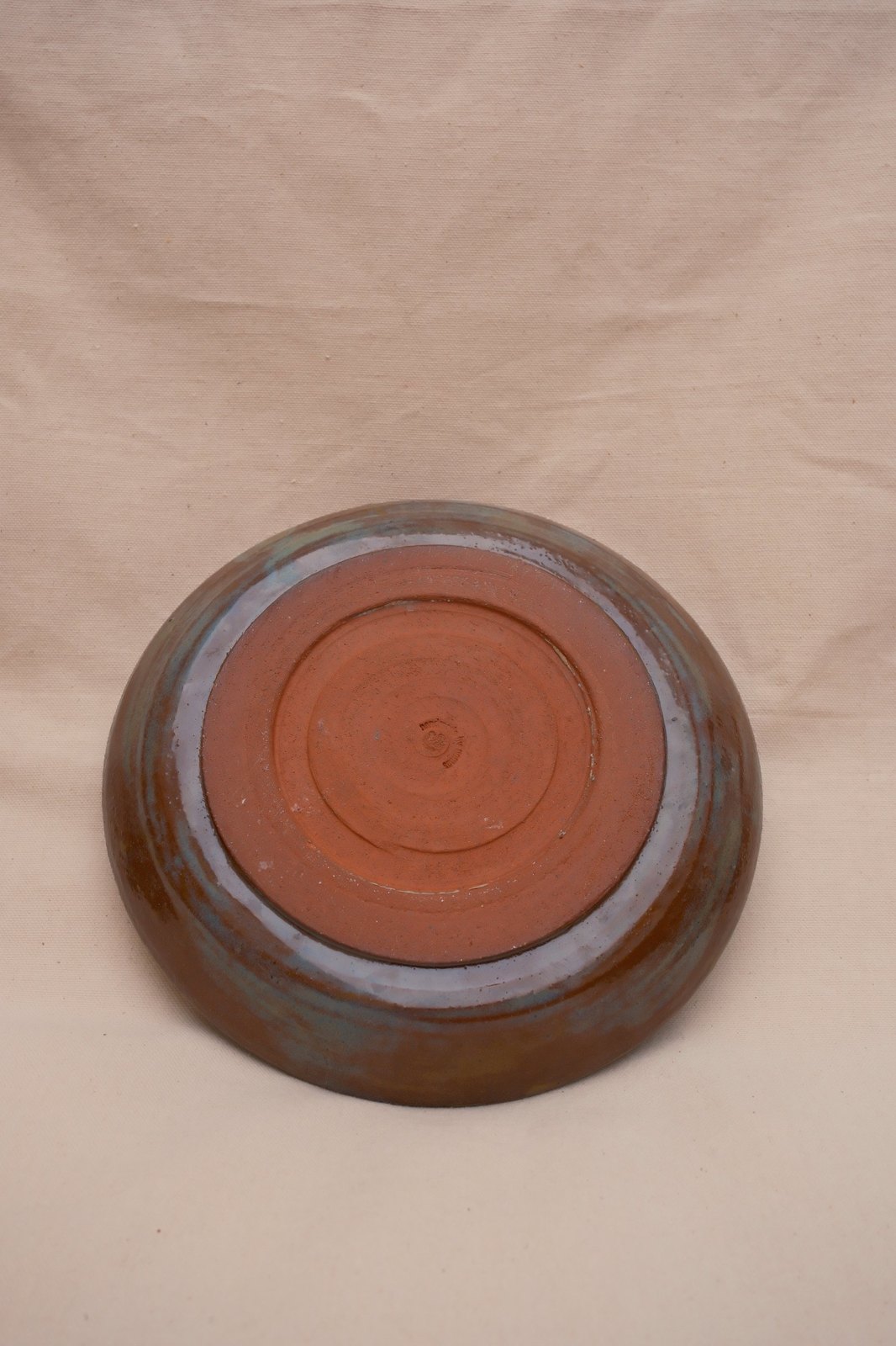 Underside of the plowl: bare terracotta foot ring with trimming lines and a small maker's stamp