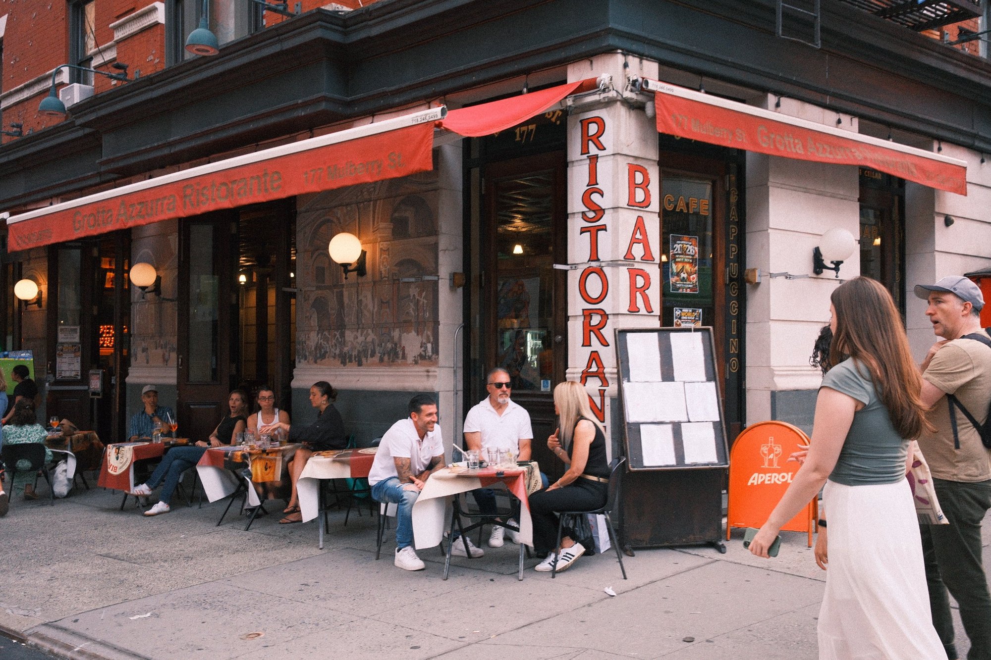 Diners at sidewalk tables under the red awnings of Grotta Azzurra