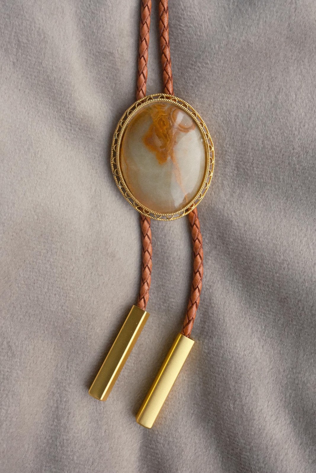 Sagebrush bolo tie: sage-green jasper cabochon streaked with amber, in a gold rope-edge bezel