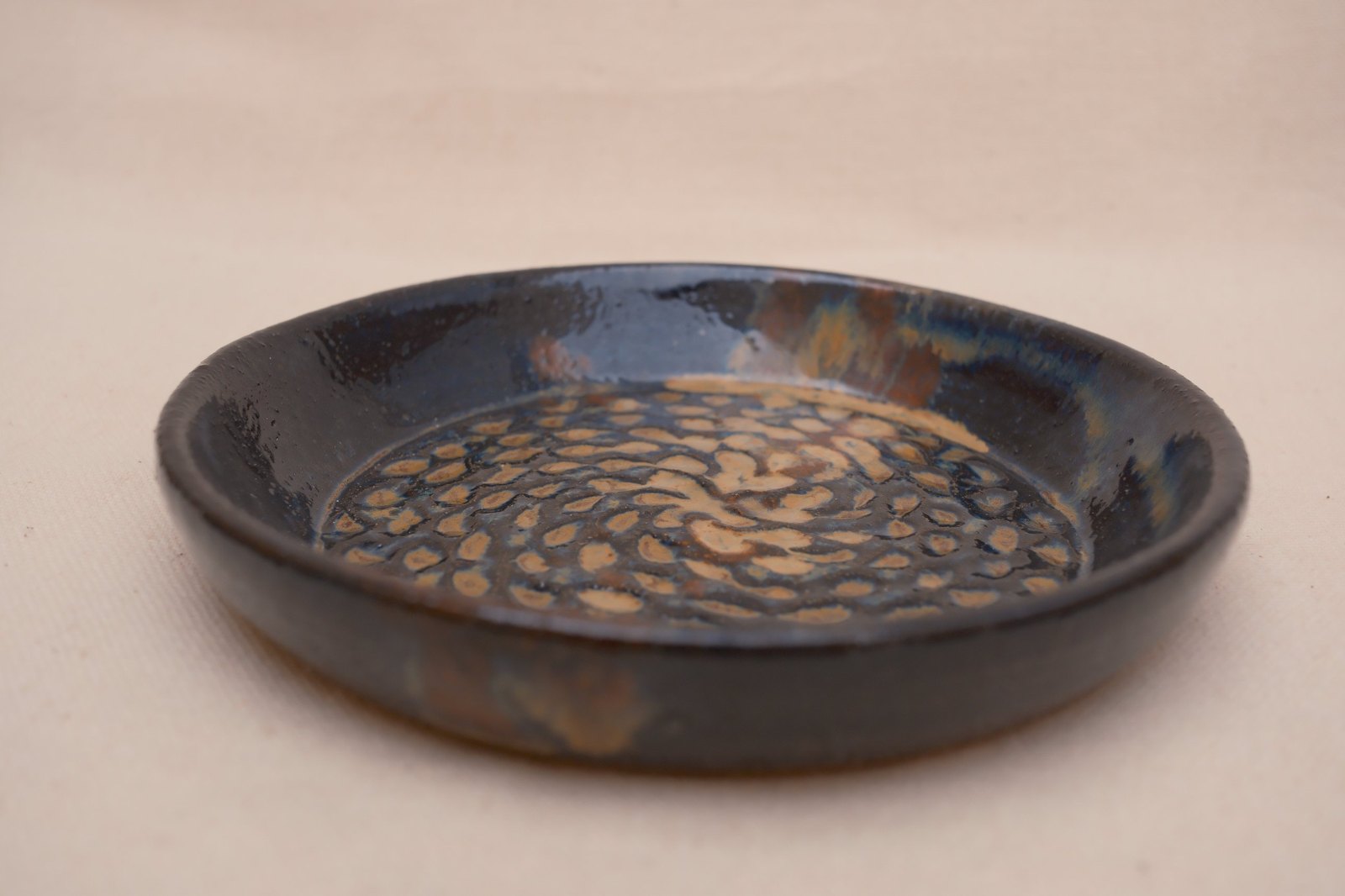 Side view showing the dish's low wall and glaze breaks
