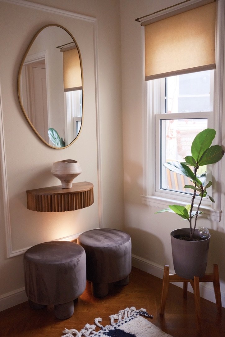Entry vignette: organic brass mirror, fluted floating shelf, velvet stools and a fiddle-leaf fig