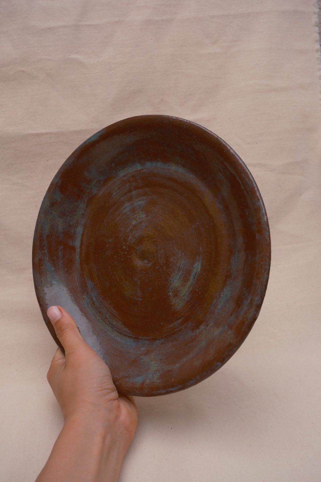 The plowl held up in one hand, showing its size and the glaze across the full surface
