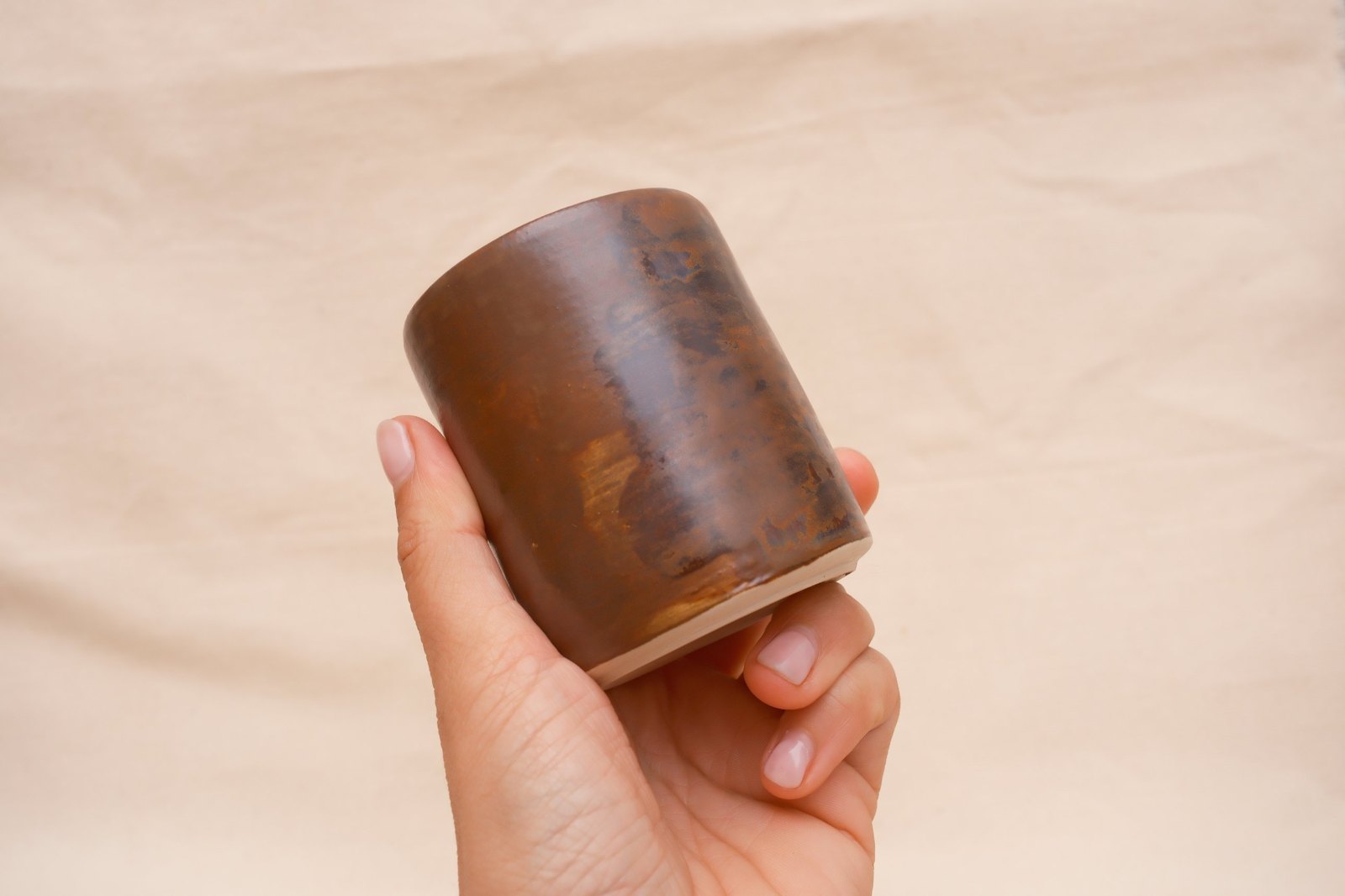 The cup tipped in the hand, light catching the glossy glaze