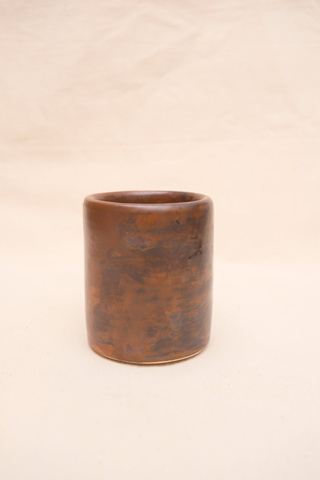 Flat white cup in Tiger's Eye and Black Walnut glaze, on linen