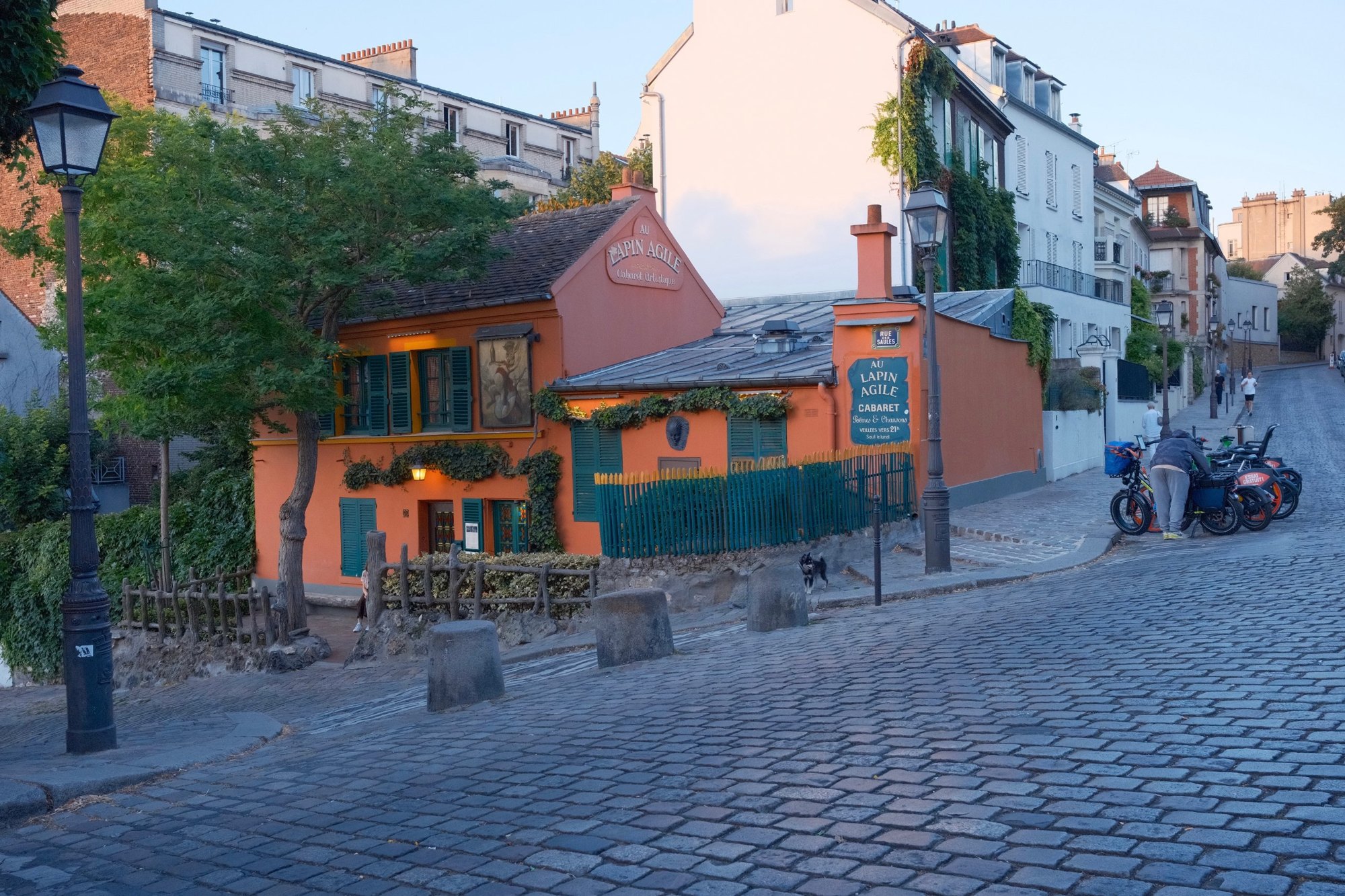 The orange Au Lapin Agile cabaret with green shutters on a cobbled Montmartre corner