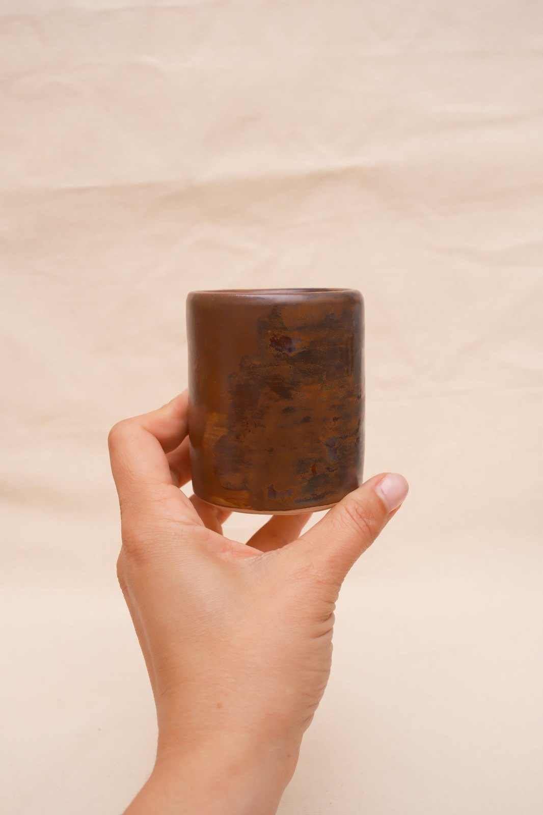 The cup held up in one hand, showing its size