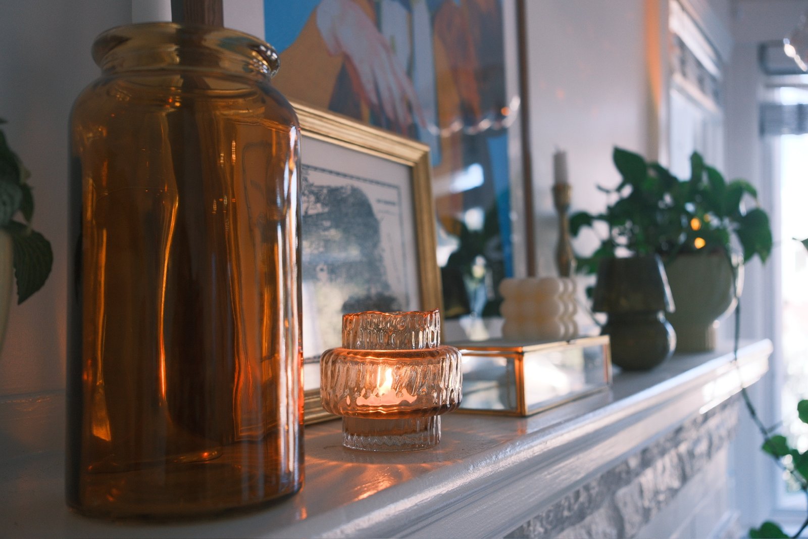 Amber glass jar and a lit tealight on a white mantel