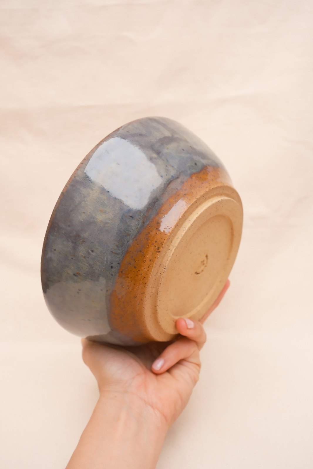 The bowl turned over in a hand, showing the trimmed foot and maker's stamp