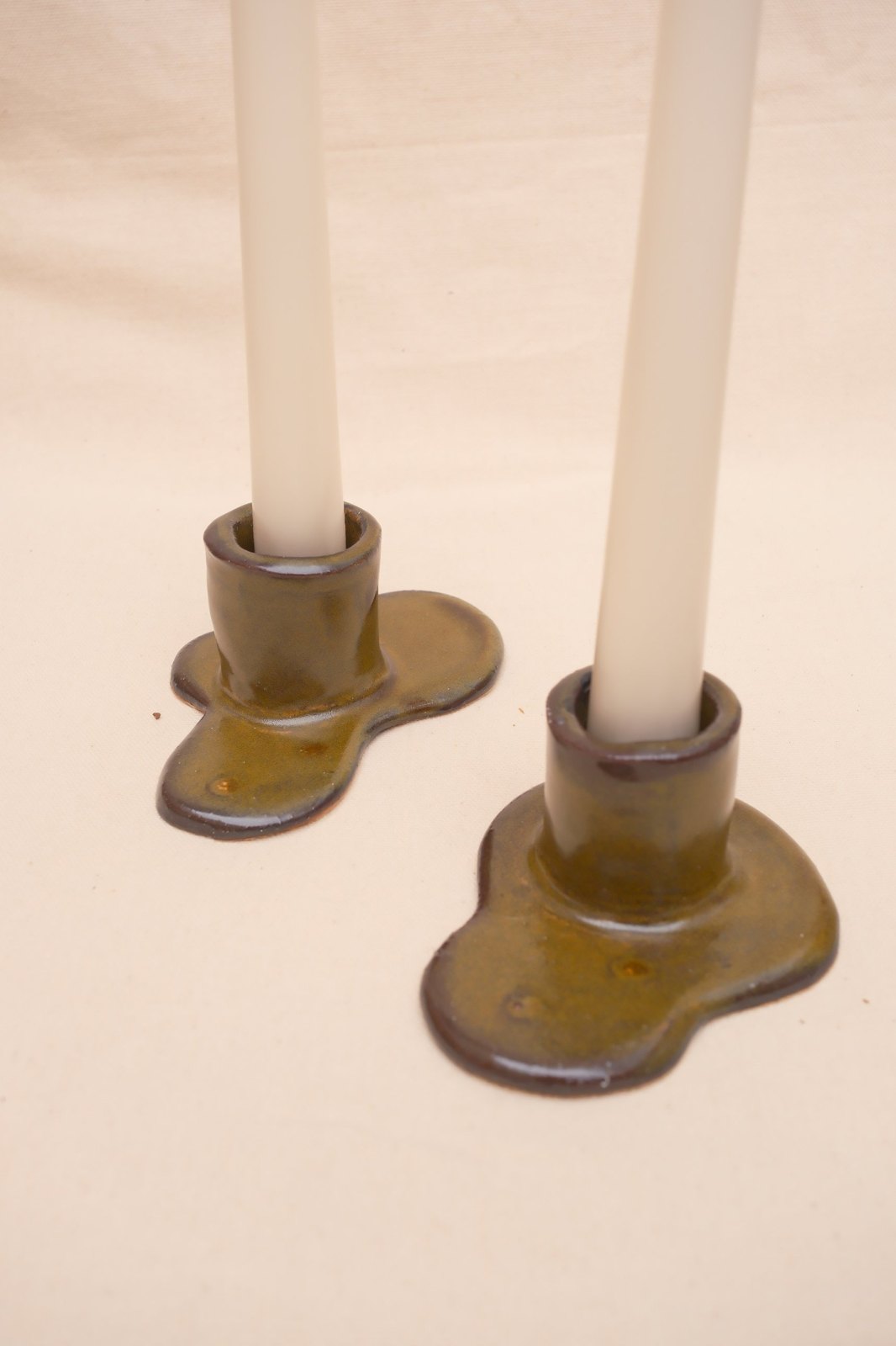 The holders from above with candles, glaze pooling in the dimples