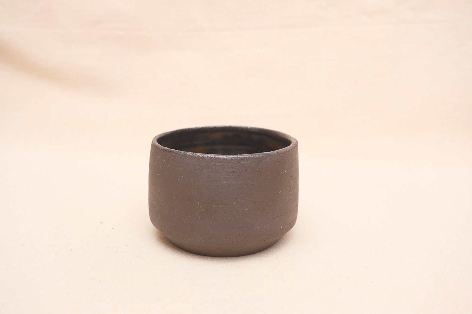 The cup straight on, its stepped foot and speckled clay