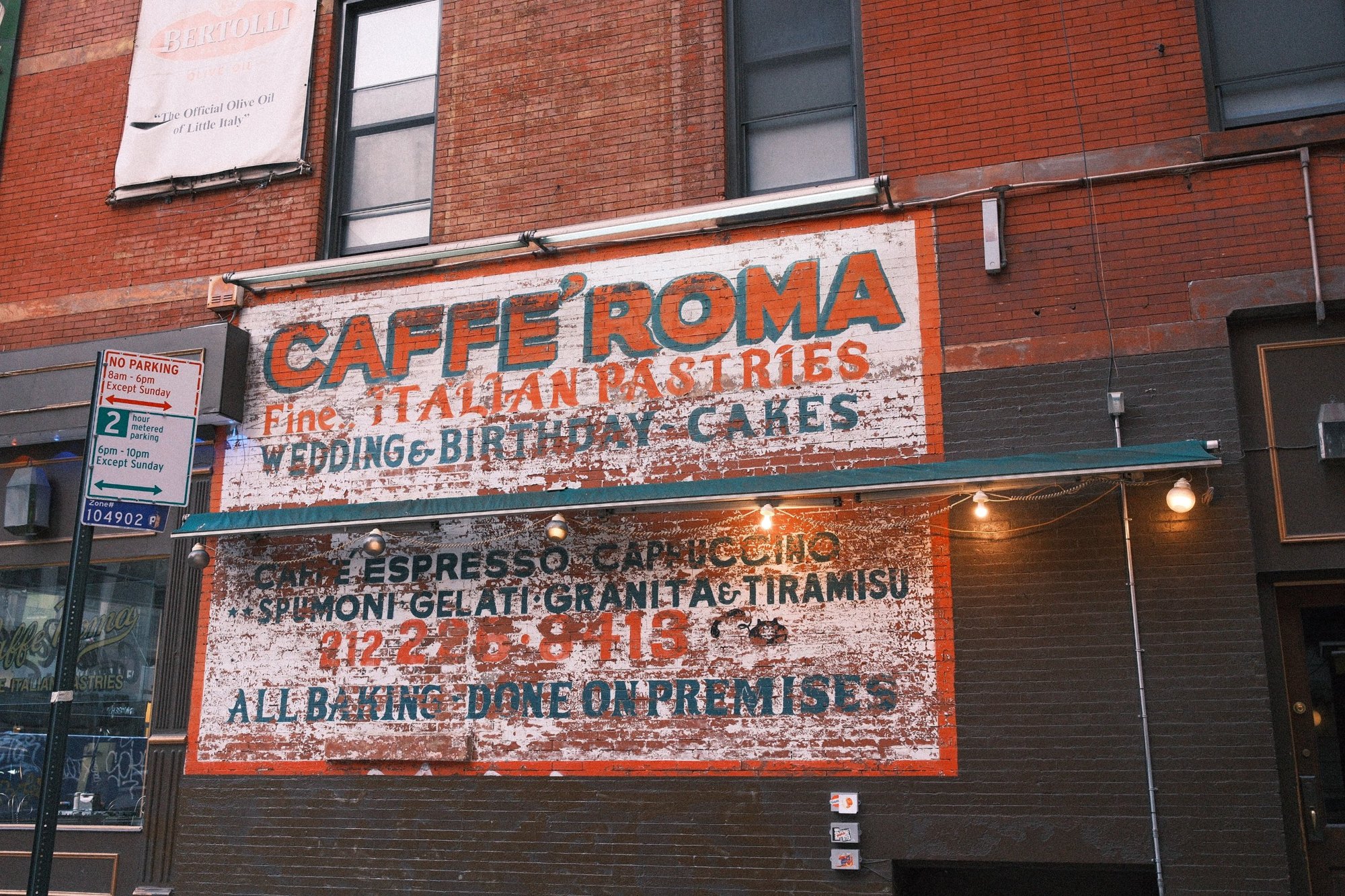 Faded hand-painted Caffe Roma sign on old brick: Italian pastries, wedding and birthday cakes