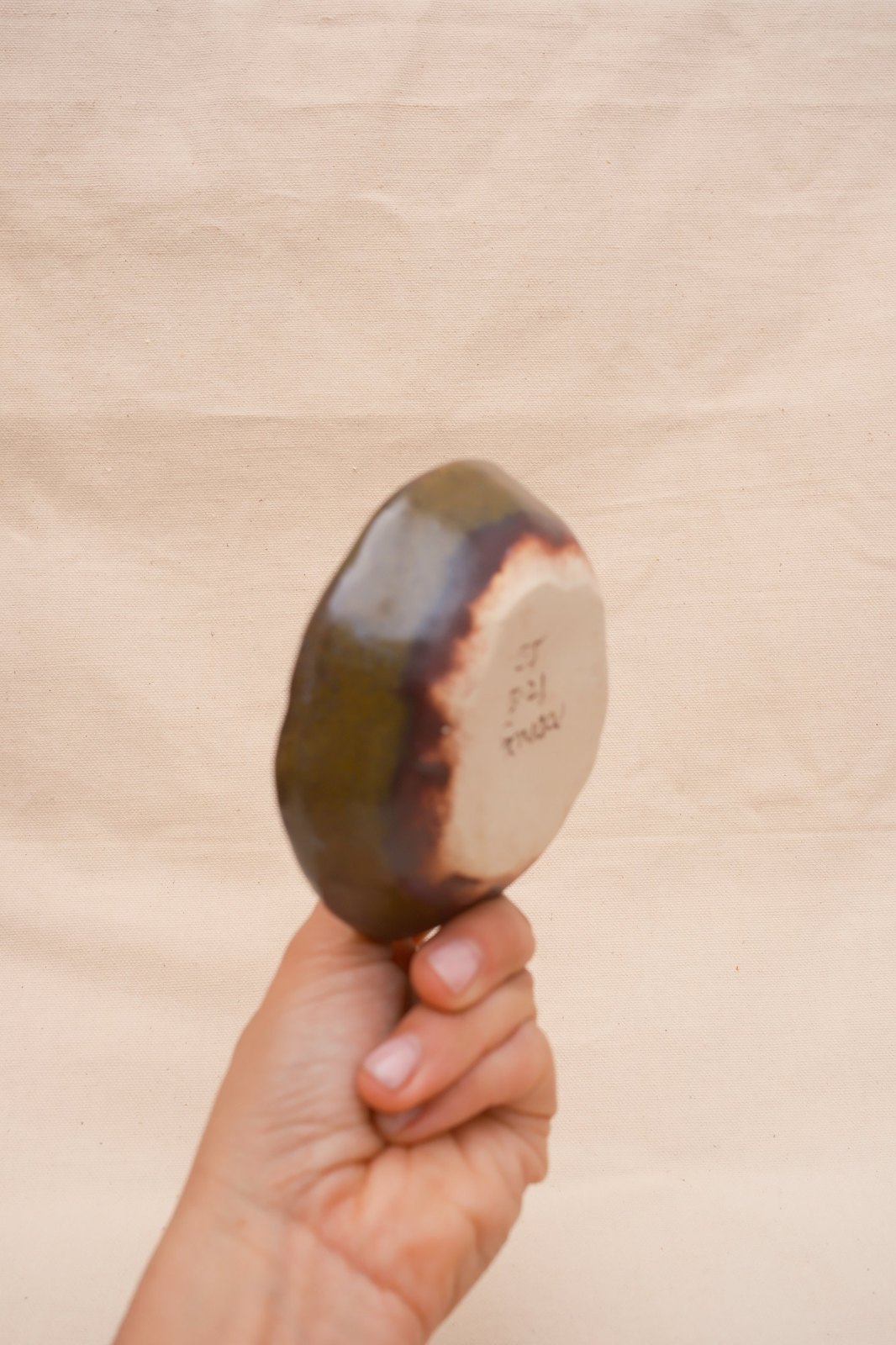 The dish turned over: bare clay foot, signed and dated, glaze breaking to brown