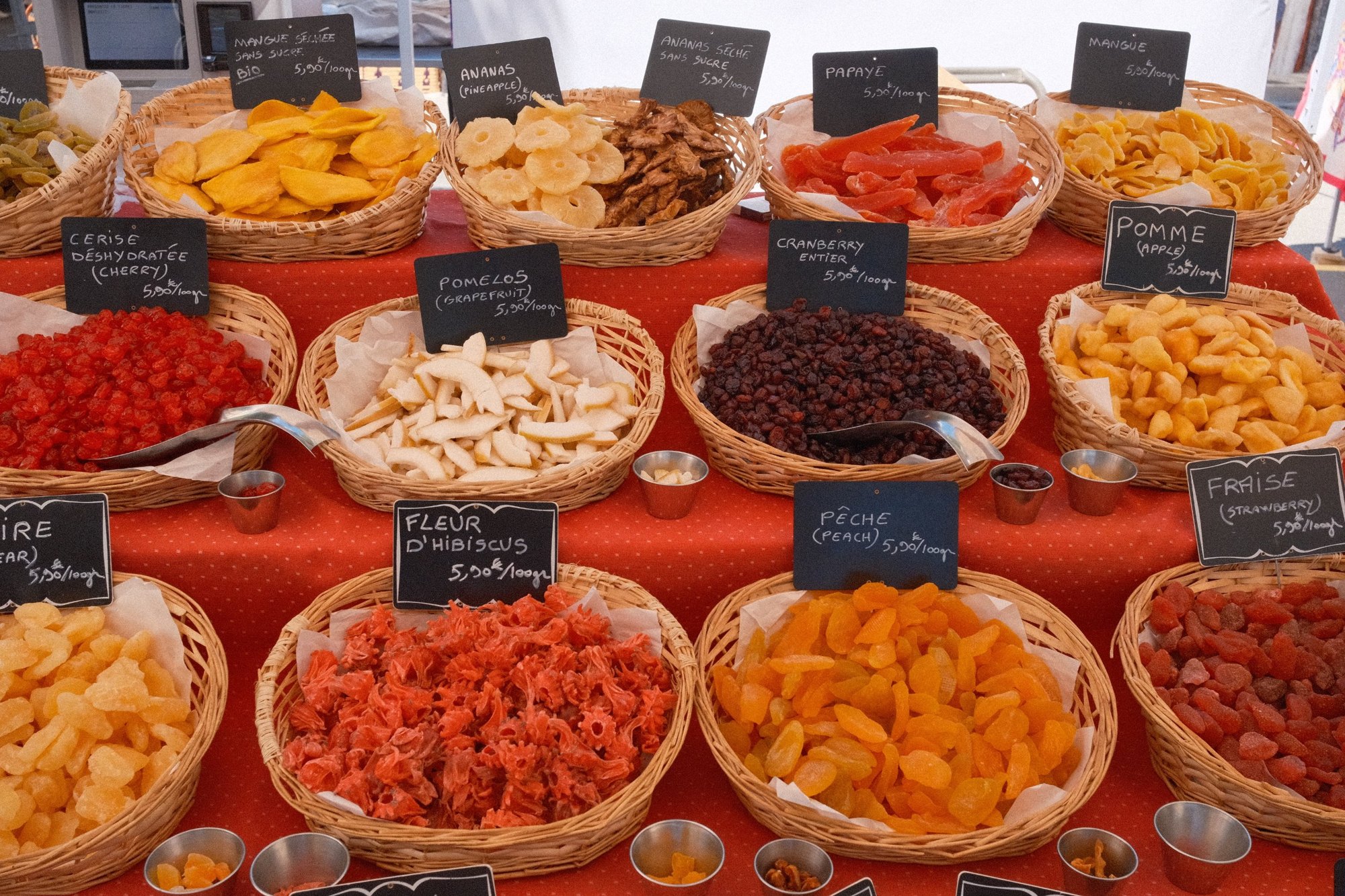 Baskets of dried mango, papaya, hibiscus and peach under chalkboard prices