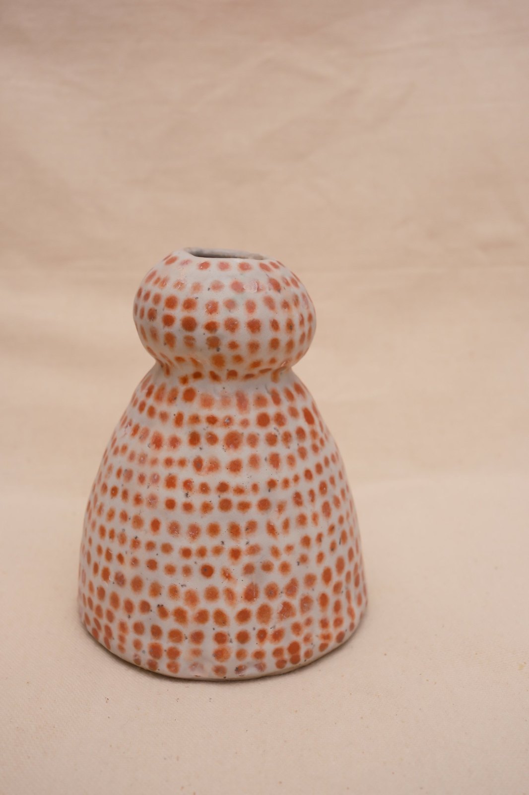 The vase from a raised angle, rows of dots wrapping the body