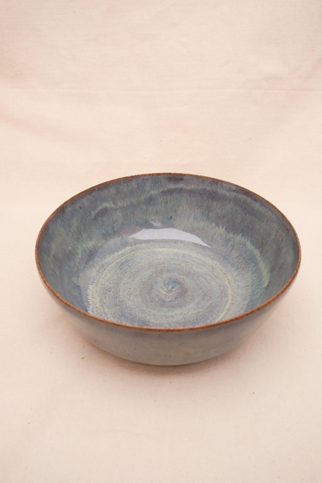 Large blue serving bowl with a rust rim, on linen