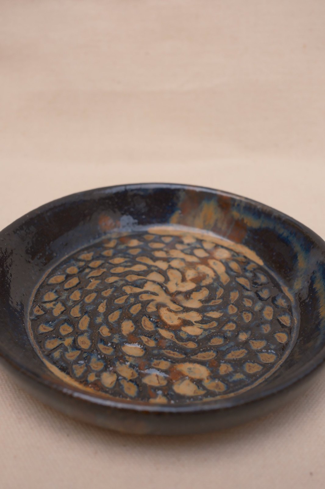 Close view of the pressed marks, tan glaze pooling in each one