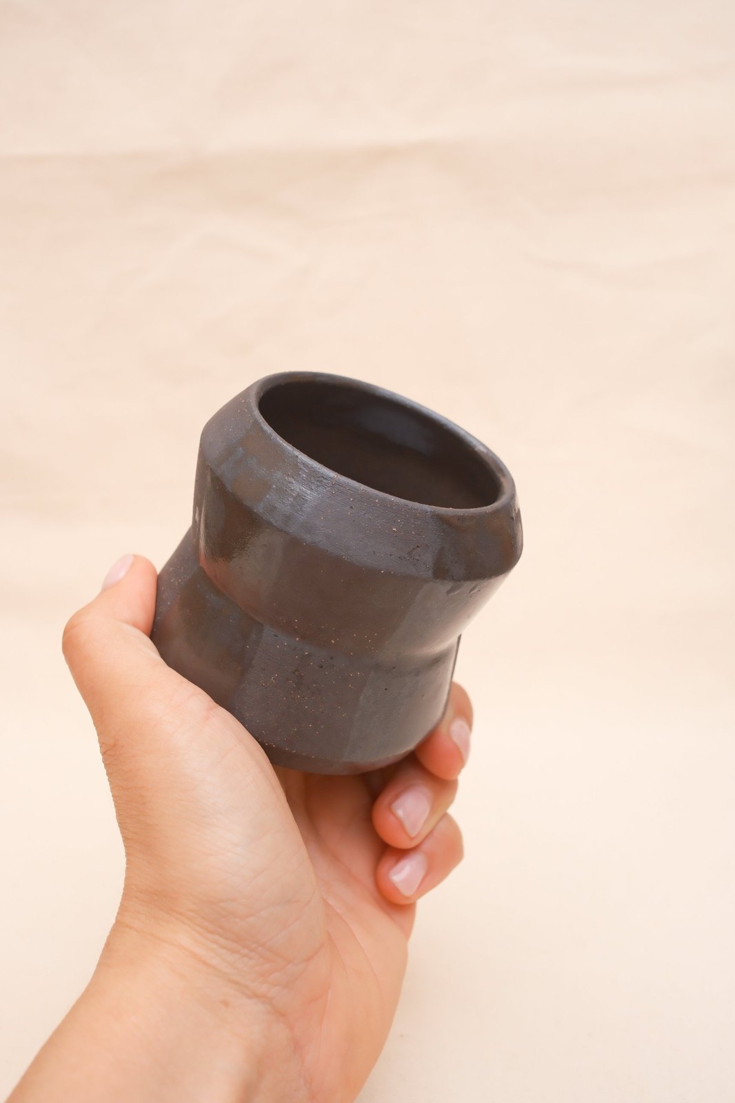 The cup tipped in the hand, showing the glazed rim and interior