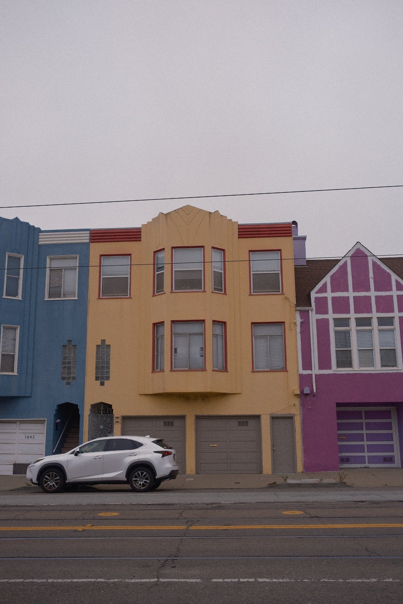 Art deco row of blue, mustard and magenta houses on a foggy avenue