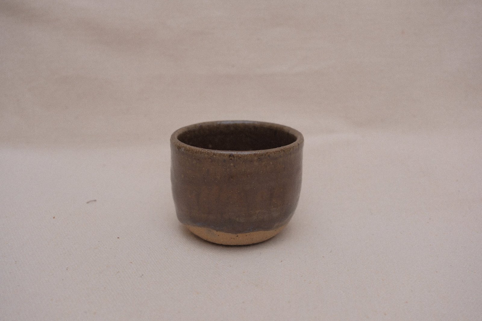 Amber cup in softer, cooler light against linen
