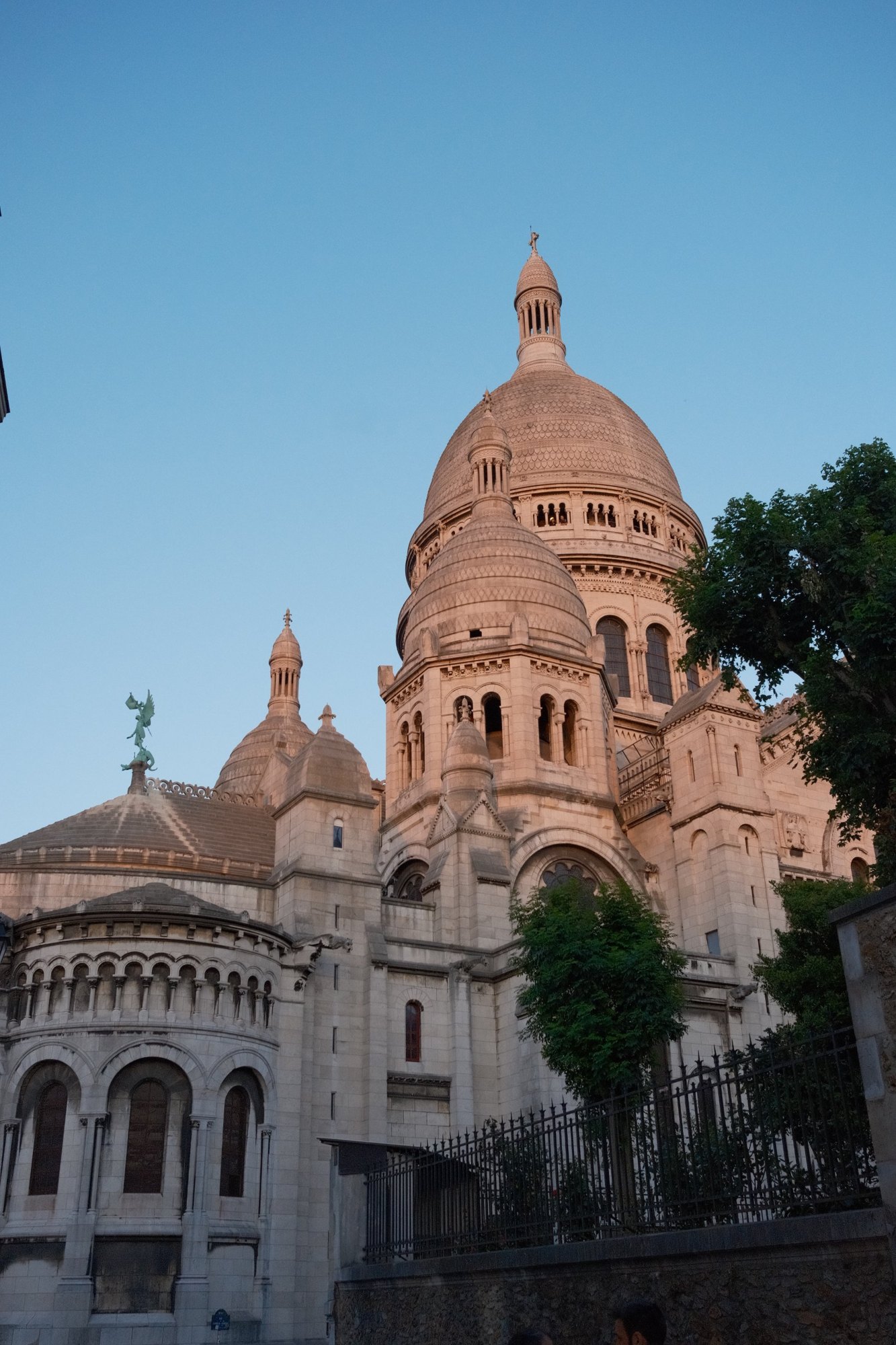 Sacré-Cœur's domes blushing pink against a clear evening sky