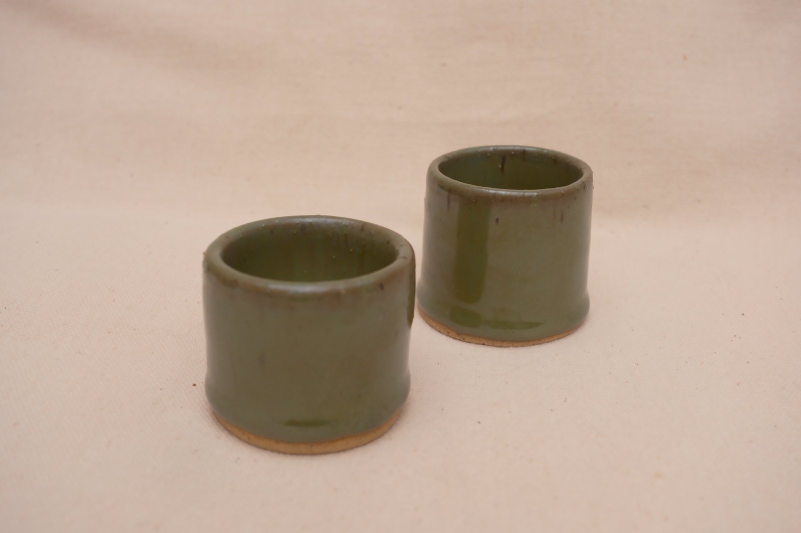 Both shot glasses from a low angle, glaze pooling near the foot