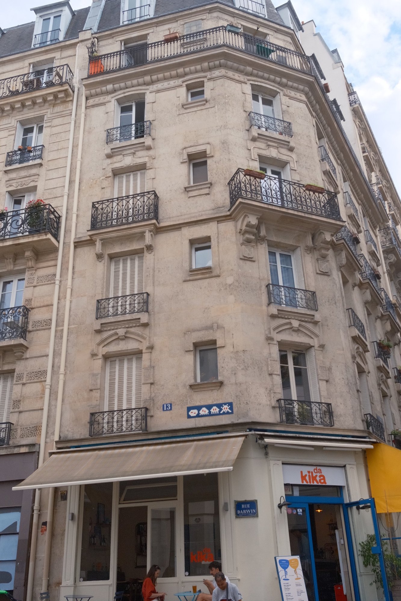 Haussmann corner building on Rue Darwin, a Space Invader mosaic above the café