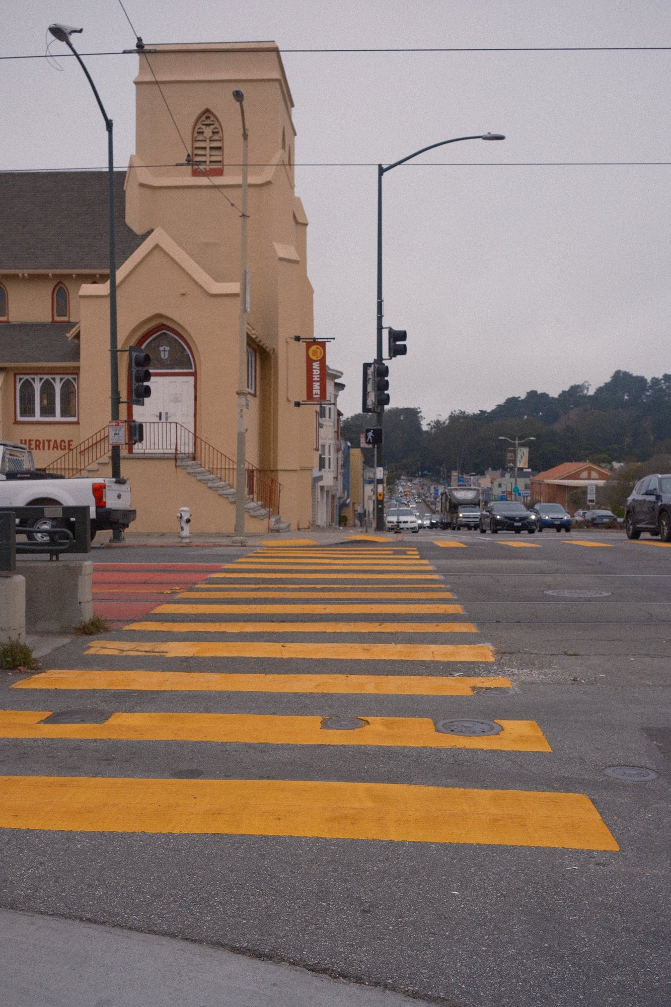 Yellow crosswalk stripes leading to a peach church on a grey day