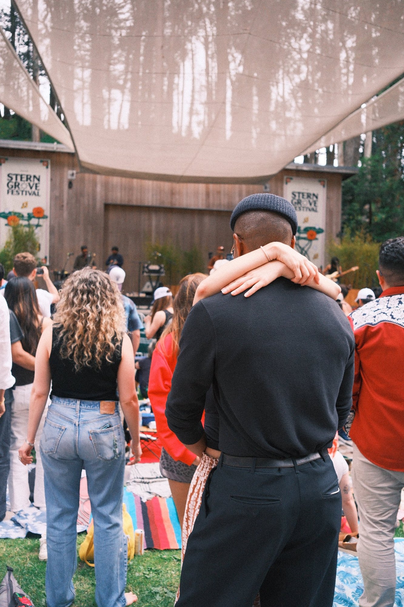 Arms wrapped around a shoulder, watching the band at Stern Grove