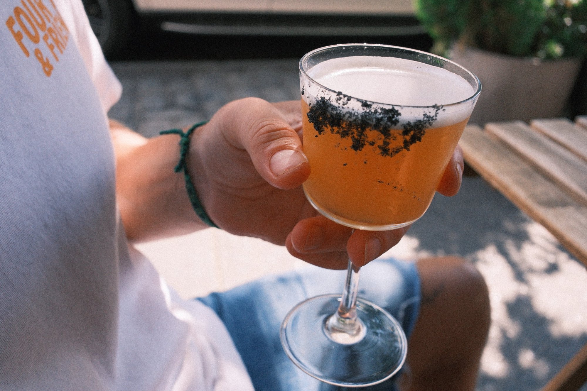 An orange cocktail with a black salt rim in the afternoon sun