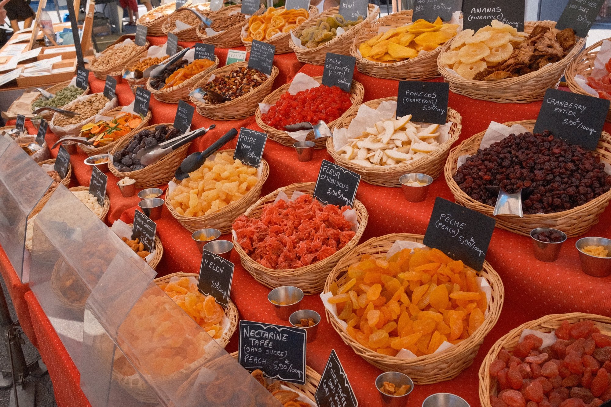 A long market table of dried fruit and nuts in wicker baskets